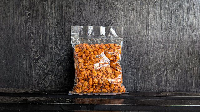 snack in clear plastic packaging on black background - Balado peeled koro bean snack is a typical Indonesian snack made from peeled koro beans and seasoned with spicy balado seasoning.