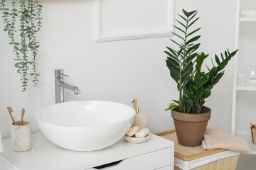 Fototapeta premium Sink bowl and cup with toothbrushes on chest of drawers in bathroom, closeup