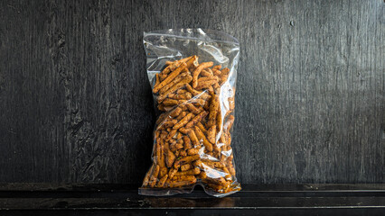 snack in clear plastic packaging on black background - Basreng pedas daun jeruk is a snack made...