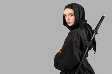 Female ninja with sword on grey background © Pixel-Shot