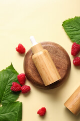 Bottle of cosmetic raspberry oil on yellow background
