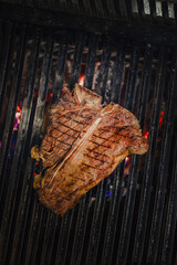 t-bone beef steak sizzling on an open flame grill