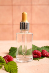 Bottle of cosmetic raspberry oil on pink table
