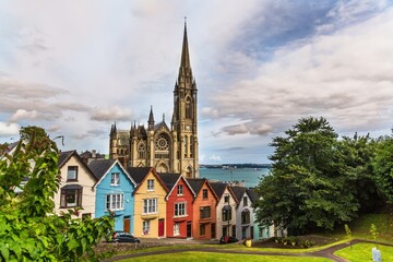 Colorful houses in front of St. Colman's Cathedral overlooking the harbor in Cobh, Ireland