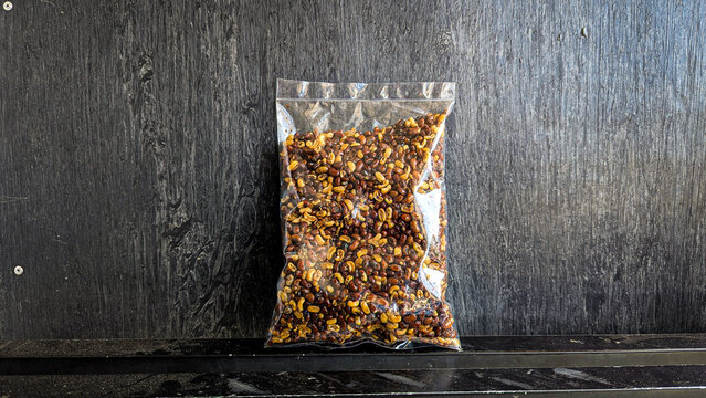 snack in clear plastic packaging on black background - Kacang krotok is a typical snack made from tolo beans, with a savory and crunchy taste. Kacang krotok is often also called kacang otok