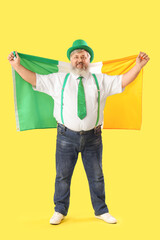 Mature man in hat with Irish flag on yellow background. St. Patrick's Day celebration