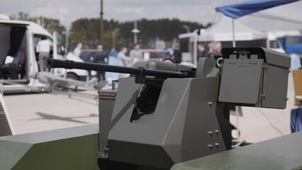 Attendees explore a military technology exhibit featuring a modern weapon system, displaying innovation and engineering in defense applications.
