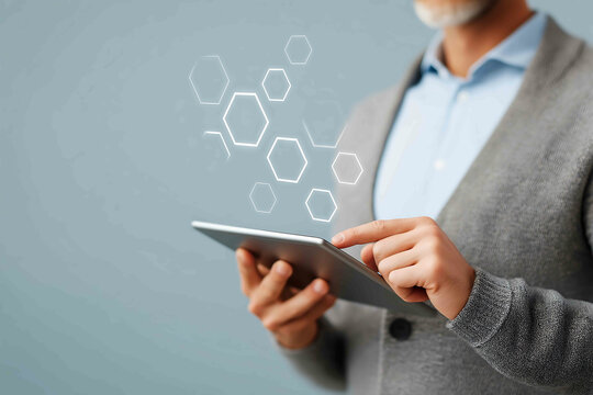A man in profile holding a digital tablet with hexagon icons softly floating around Focus on professional development and techenhanced teamwork