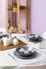 Stylish table setting with candles, wheat and grey napkins in dining room. Closeup