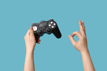 Female hands with game pad showing OK on blue background
