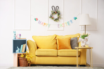 Interior of festive living room with yellow sofa, garland, flowers and Easter decorations on coffee table