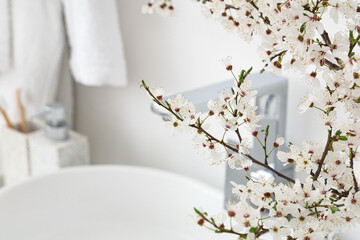 Blossoming branches near sink in bathroom, closeup