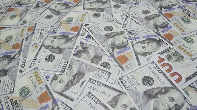 Money falling from above. Scattered one hundred dollar bills on dollar bill background, financial freedom concept. Close up.
