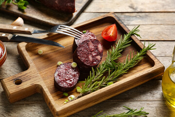 Board with tasty blood sausage on wooden background
