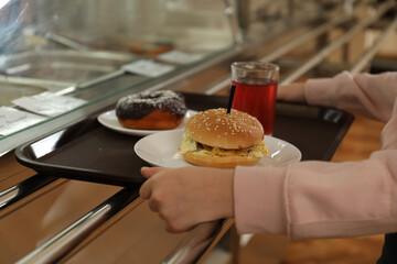 Little girl with plastic tray near serving line in canteen, closeup. School food