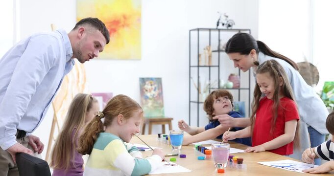 Kids with teachers at painting lesson, camera moving right. Learning to draw