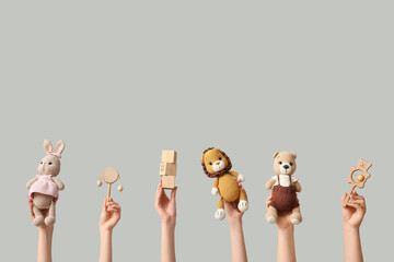 Hands holding baby toys on grey background