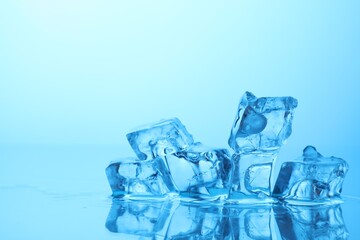 Cubes of clear ice on light blue background, closeup. Space for text