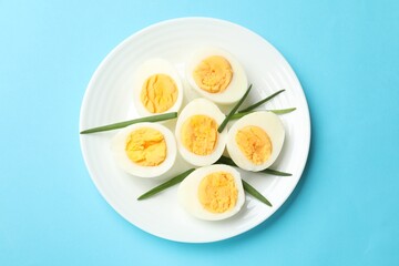 Boiled eggs and green onions on light blue background, top view