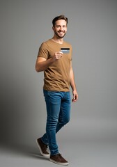 Portrait Man Holding Credit Card Happy in Studio Setting with Gray Backdrop