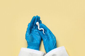 Doctor's hands with sperm cell on beige background