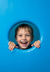 Portrait of a Happy Young Boy Smiling Through Blue Hole Indoors