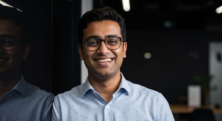 Portrait Of A Smiling Indian Man With Glasses In A Modern Office
