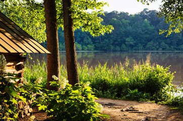 A sunset landscape at the back of a log cabin with trees by a lake in the woods at Yates Millpond County Park in Raleigh, North Carolina. USA.