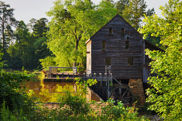 A nice sunny view of the old timber watermill by the waterfall dam at Yates Millpond Park in Raleigh, North Carolina before sunset.
