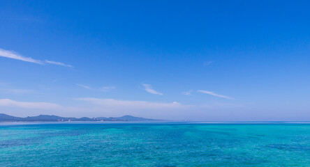 Century Beach in Nago, Okinawa—turquoise waters meet a concrete pier, with a distant cityscape beyond the horizon.