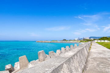 Century Beach in Nago, Okinawa—turquoise waters meet a concrete pier, with a distant cityscape beyond the horizon.