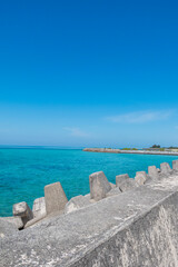 Century Beach in Nago, Okinawa—turquoise waters meet a concrete pier, with a distant cityscape beyond the horizon.
