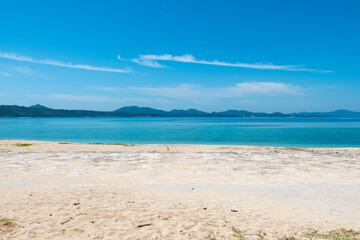 Century Beach in Nago, Okinawa—turquoise waters meet a concrete pier, with a distant cityscape beyond the horizon.