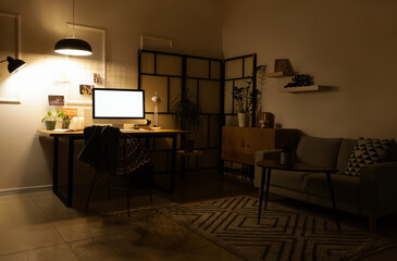 Interior of dark office with workplace, sofa and glowing lamps