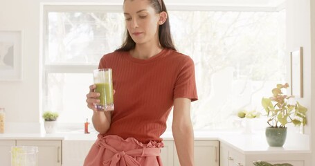 Smiling woman in kitchen using smartphone while preparing healthy smoothie - Powered by Adobe