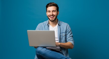 Portrait Of Smiling Man with Laptop in Denim Shirt On Blue Backdrop
