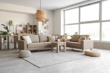 Interior of stylish living room with cozy grey sofas, coffee table and houseplants