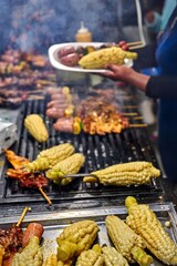 Grilled corn, sausages and marinated skewers are served at street food stall in Ecuador. Vibrant local flavors and traditional festive street food culture