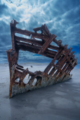 Shipwreck on the sandy shore under dramatic skies