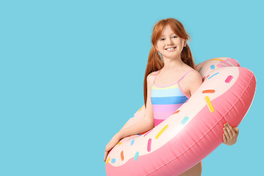 Little redhead girl with inflatable ring on blue background