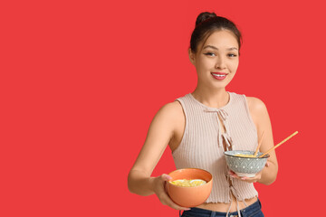 Young Asian woman with tasty ramen on red background