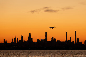 Airplane landing over the city skyline at dusk
