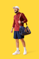 Young man with sports bag on yellow background