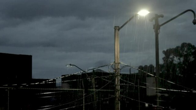 Faroles de calle iluminando las gotas de lluvia cerca de ellos. 