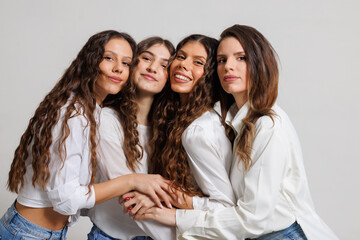 Group of Four Women Embracing in a Studio Setting in Coordinated Outfits