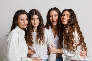 Four happy young women laughing and posing together indoors
