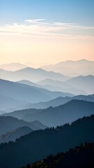 Fototapeta premium Misty mountain ranges recede into the distance, creating a layered, atmospheric vista at sunrise.
