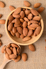 Raw almond nut seed in wooden spoon and bowl, Top view