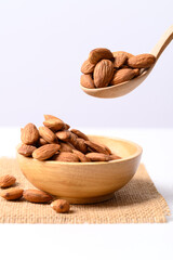 Raw almond nut seed in wooden bowl and spoon on white background