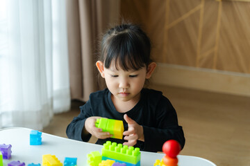 3-year-old girl happily playing with toy blocks at home.Childhood and children's meditation concept